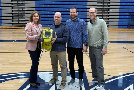  Left to right, Jessica Bortner hands off an AED to the Sports Medicine Team, represented by Community Hospital Athletic Trainer Evan Dekok and Physical Therapists Brett Burton and Ryan Hardin.